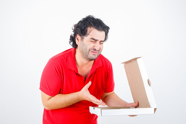 男人一个穿着红色t恤的帅哥打开纸盒 失望地把手伸向盒子 神情阴沉 俯瞰前方举止沮丧成人