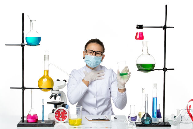 飞溅前视图穿着医疗服的女化学家 戴着面罩 白色背景上有绿色溶液飞溅实验室病毒化学covid-实验室实验室烧杯