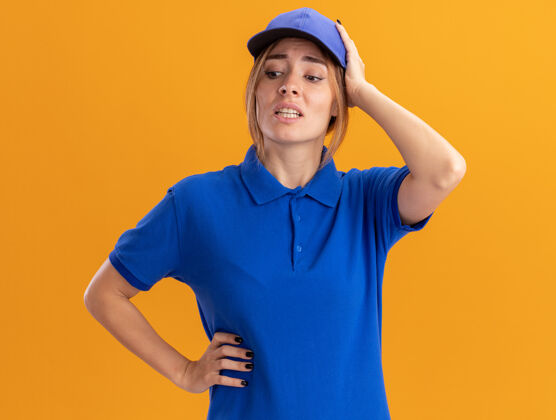 焦虑焦急的年轻漂亮的女送货员穿着制服 把手放在头上 低头看着橘子年轻交货制服