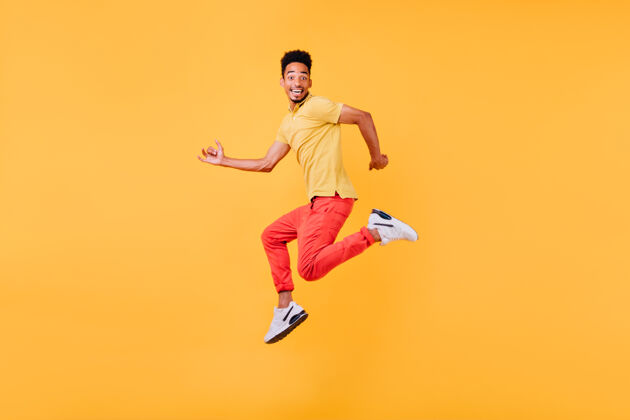 表情有趣的非洲男模摆出惊讶的微笑室内照片的运动黑人男子跳跃黑人学生年轻