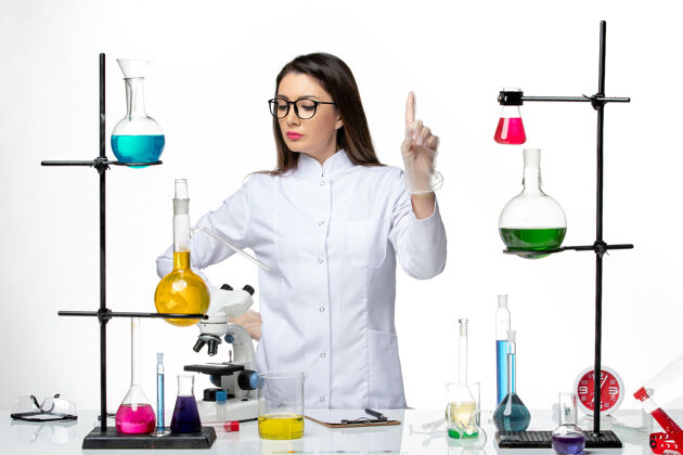 医疗正面图：穿着无菌医疗服的女化学家在白色背景病毒冠状病毒上用不同的溶液工作-实验室大流行科学视图正面不同