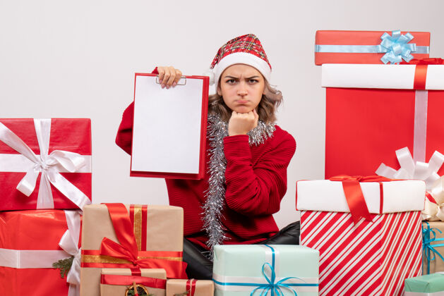 快乐正面图年轻女性围坐在圣诞礼物旁 带着纸条微笑周围购物