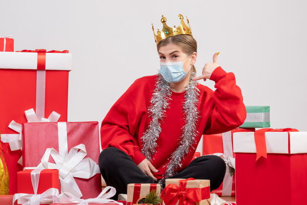 礼物正面图：年轻女性戴着无菌面具坐着 手里拿着圣诞礼物人礼物年