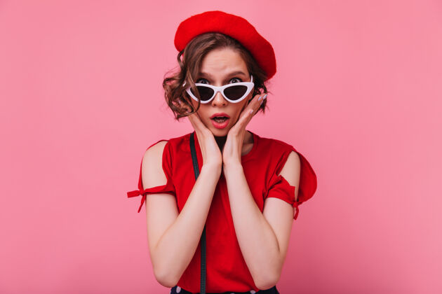 有趣失望的法国女模特戴着太阳镜摆姿势不幸的短发女人戴着红色贝雷帽粉色表情优雅