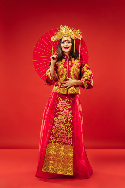 时尚中国传统的优雅女子在红色背景的工作室里新美女女士