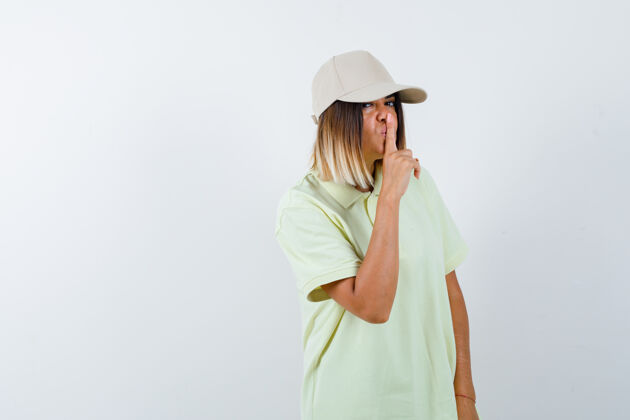 手势年轻女性穿着t恤 戴着帽子 摆出沉默的姿态 严肃地看着前方帽子时尚水疗