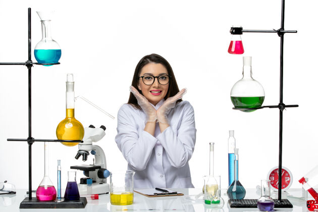 液体前视图穿着白色医疗服的女化学家坐在白色背景上微笑着摆姿势实验室科学病毒冠状病毒大流行玻璃葡萄酒医学