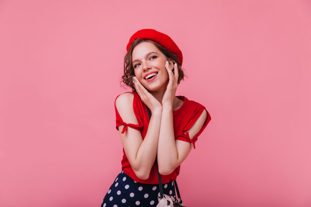 休闲迷人的法国女模特摆出有趣的微笑浪漫的女孩在红色服装与贝雷帽肖像休息人物