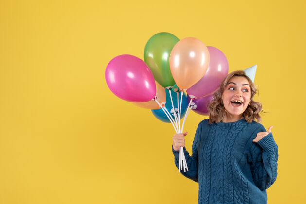 五颜六色正面图：带着彩色气球的年轻女性一年颜色女人