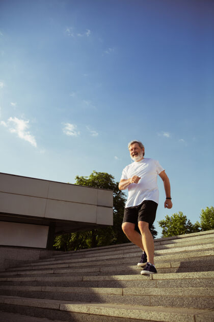 乐趣在城市街道上戴着臂章或健身的高级男子跑步者高加索男模在夏天的早晨练习慢跑和有氧训练健康的生活方式 运动 活动理念运动员耳机公园
