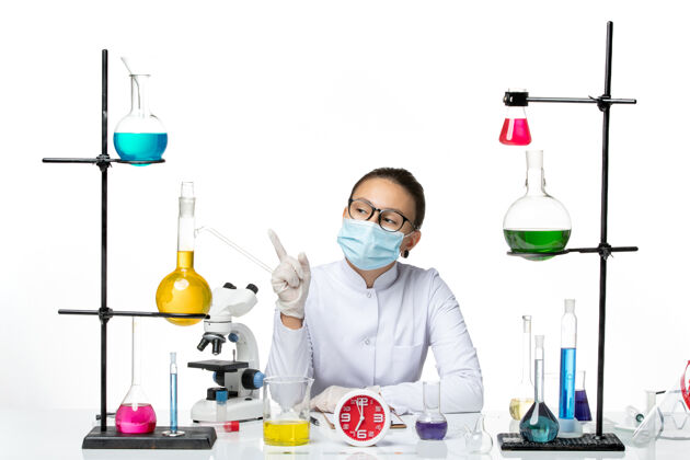 专业前视图穿着白色医疗服的女化学家戴着面具坐在白色背景上思考化学家病毒-飞溅实验室医学飞溅医学