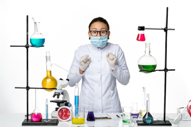 研究前视图：身穿医疗服 戴着口罩的女化学家站在白色背景上病毒化学实验室的covid-splash西装医院外套