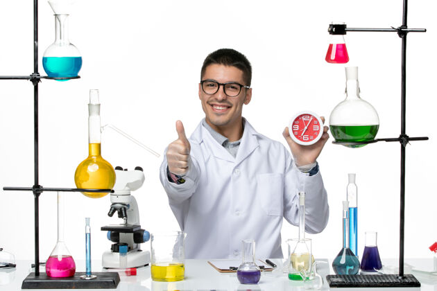 科学正面图身穿白色医疗服的男性化学家拿着时钟 微笑着站在白色背景的柯维病毒疾病科学实验室人视图专业