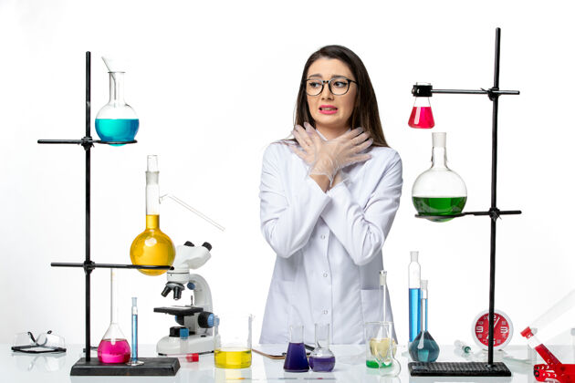 烧杯正面图：身着无菌医疗服的女化学家站在桌子旁 拿着白色背景病毒疾病的解决方案-实验室流行病科学专业周围人