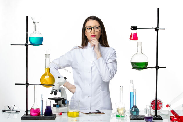 消毒正面图：穿着无菌医疗服的女化学家站在桌子旁 拿着白色背景病毒疾病病毒的解决方案-大流行科学病毒实验室专业