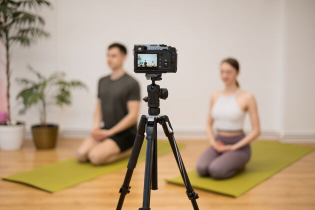 老师瑜伽教练在家里的摄影棚里教授在线训练课程运动教练展示瑜伽姿势 讲解 给更多的提示流瑜伽运动装