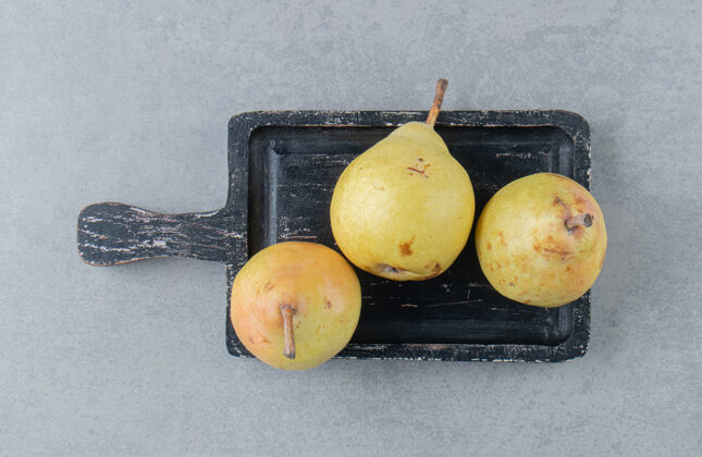 板黄色的梨子放在黑色的大理石板上营养新鲜配料