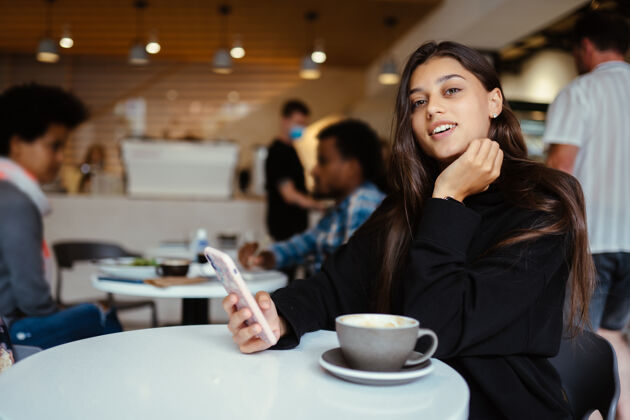 芳香坐在咖啡馆里使用智能手机的女学生画像手机肖像享受
