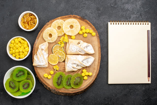 盘子在灰色的桌子上俯瞰美味的糕点和干菠萝环和猕猴桃干午餐饭
