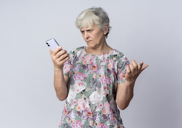抱着不高兴的老妇人拿着电话 看着隔离在白墙上的电话女人老人电话