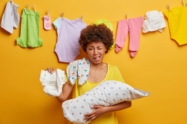 抑郁忙碌而负责的母亲对换尿布 照顾新生儿和保持清洁 闻着难闻的臭味 抱着裹在毯子里的婴儿感到厌恶育儿 家庭和护理理念儿子小童年