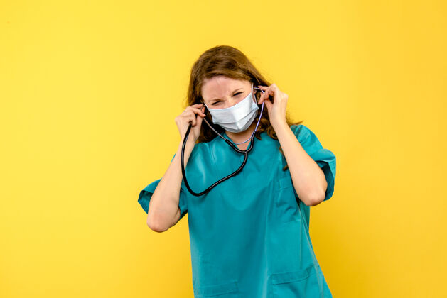 成人黄色地板上戴着口罩的女医生的正视图医院医疗保健黄色人制服