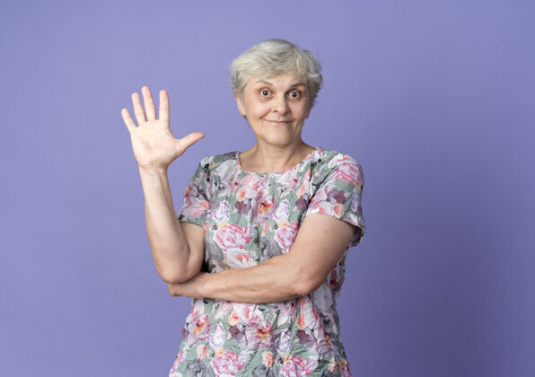 女人兴奋的老妇人举起手孤立在紫色的墙上老兴奋举起来