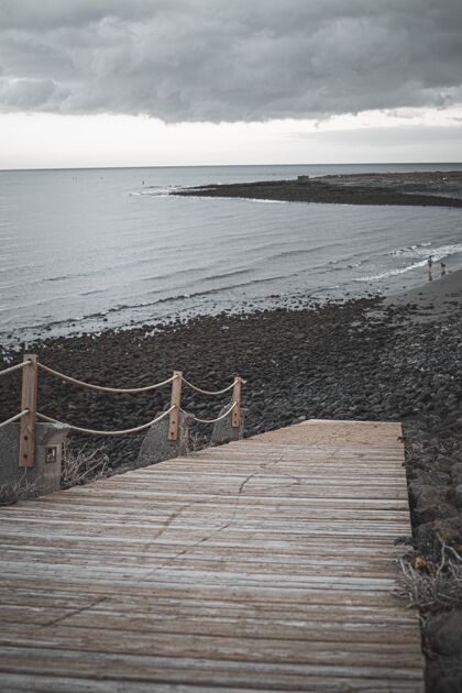 放松在多云的天空下用木桥垂直拍摄海滩路光沙滩