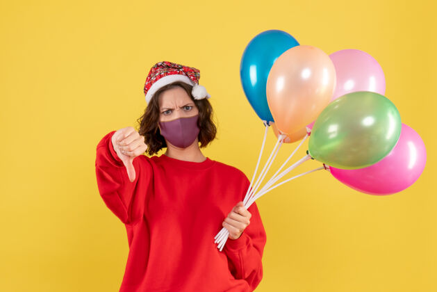 生日正面图年轻女性拿着气球 戴着黄色的无菌面具前面庆祝工艺