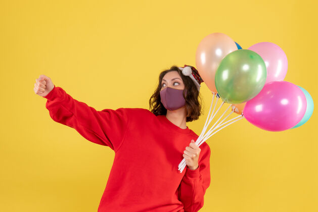 颜色正面图年轻女性手持气球 戴着黄色的无菌面具气球广播消毒