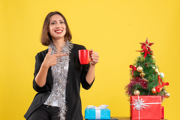 黄色圣诞节的心情与情感美丽的女士站在办公室 并指出在黄色的办公室红杯头发快乐杯子