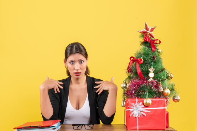 心情新的一年心情与好奇的年轻女子穿着西装装饰圣诞树在办公室欢呼漂亮快乐