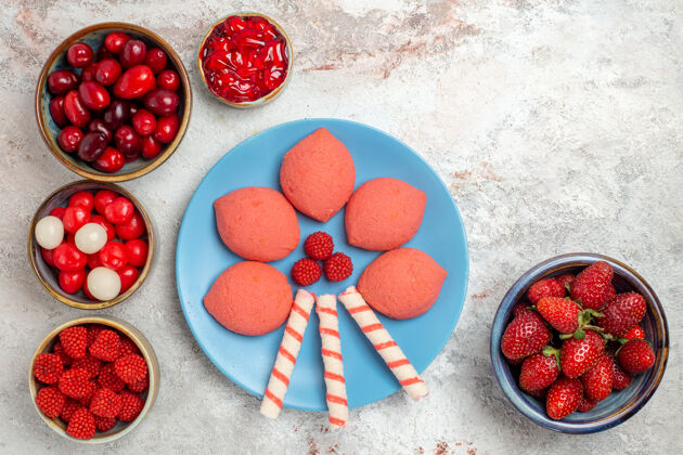 顶部白色桌面上有新鲜水果 覆盆子 草莓和山茱萸 还有饼干生的饼干甜点