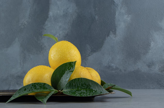 营养一小堆柠檬和树叶放在大理石上的华丽托盘上叶华丽美味