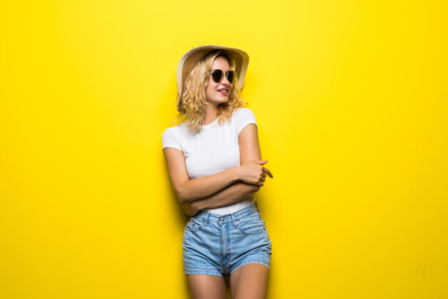裤子画像戴草帽的年轻女子在五颜六色的黄色墙上摆姿势女人颜色自信