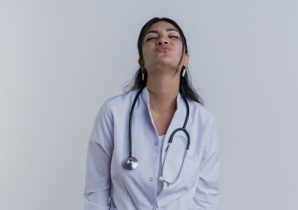 女人年轻的女医生穿着医用长袍 戴着听诊器 闭着眼睛做亲吻动作穿吻年轻人