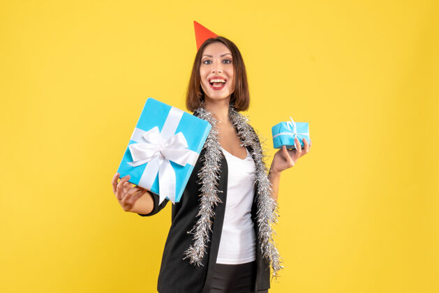 头发圣诞气氛与骄傲的商务女士西装与xsmas帽子显示她的礼物在黄色圣诞节礼物西装
