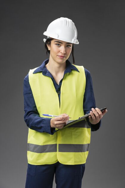头盔带剪贴板的肖像女工程师女性写作剪贴板