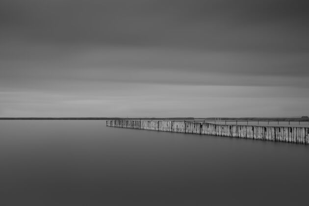 平静风暴云下海边一个长码头的灰度照片大海黑白海洋
