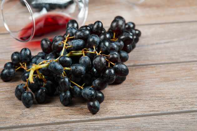 食物一束黑葡萄和一杯葡萄酒在木制背景上高质量的照片表面自然葡萄酒