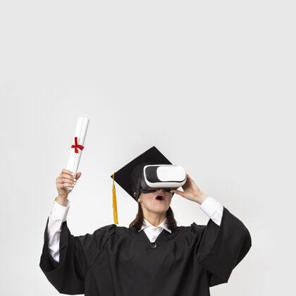毕业穿着毕业礼服戴毕业帽戴着虚拟现实耳机的女人虚拟现实眼镜技术虚拟现实