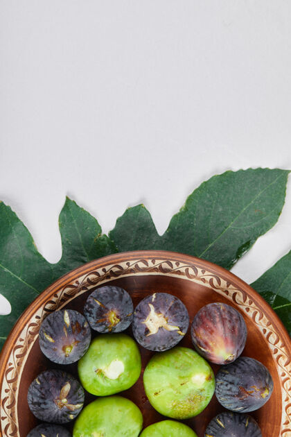 盘子绿色和黑色无花果在陶瓷板和白色背景上高品质的照片食物陶瓷叶子