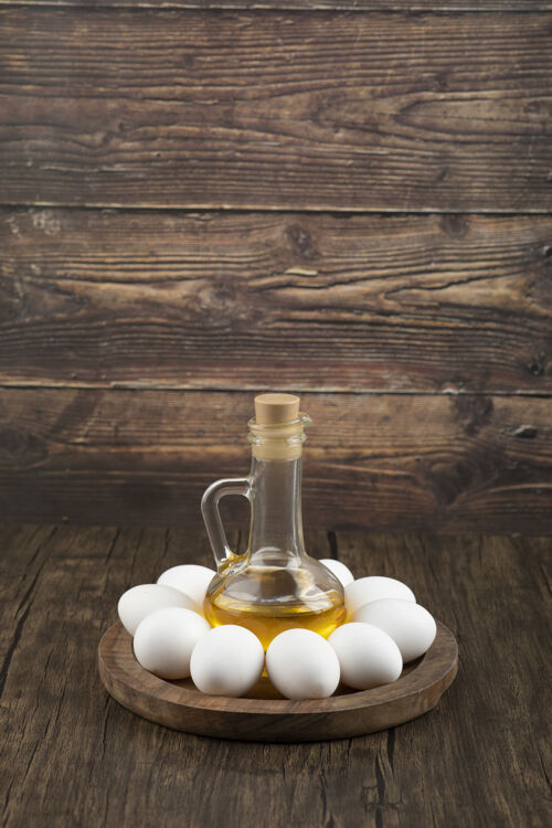 鸡肉生白鸡蛋和一瓶橄榄油放在木板上蛋白质食品玻璃