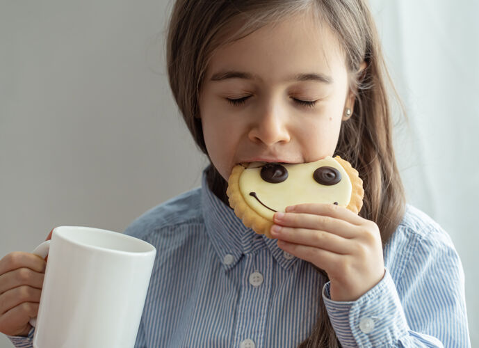 姜饼一个小学女生正在吃早餐 早餐里有牛奶和笑脸形状的有趣饼干女学生牛奶饼干