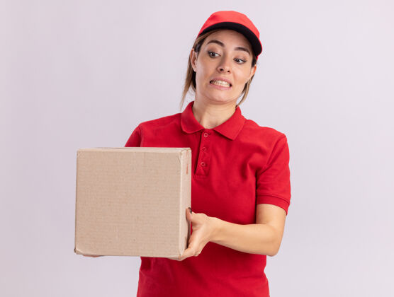 焦虑焦急的年轻漂亮的女送货员 穿着制服 手里拿着卡片盒 看着隔离在白墙上的卡片盒衣服脸人