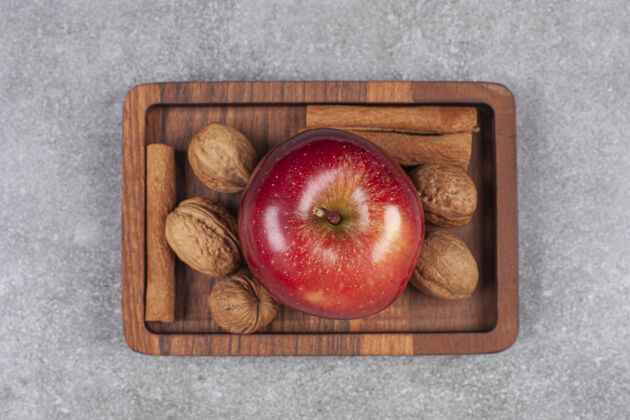 小吃红苹果 核桃和肉桂棒放在木盘上成熟的自然盘子