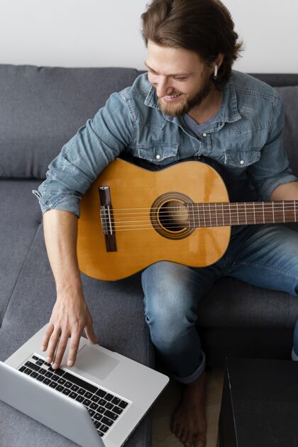 在家里中枪笑脸人吉他和笔记本电脑生活方式放松乐器