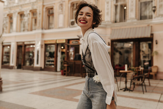 衣服乐观的女人 卷发牛仔裤真诚的微笑在城市里酷女人在街上穿黑色蕾丝的浅衬衫城市台阶城镇