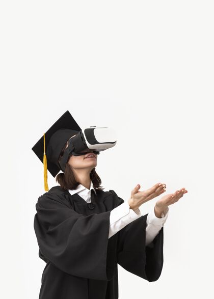 虚拟现实穿着毕业礼服戴毕业帽戴着虚拟现实耳机的女人毕业帽设备女性