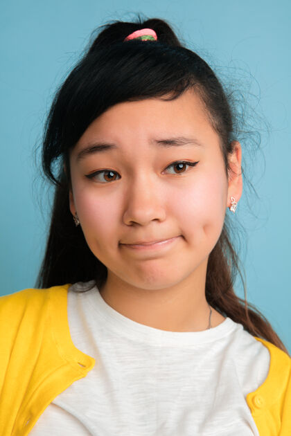 手亚洲青少年的特写肖像画孤立在蓝色工作室背景上美丽的深褐色长发女模特人类情感的概念 面部表情 销售 广告看起来很悲伤年轻人女孩员工